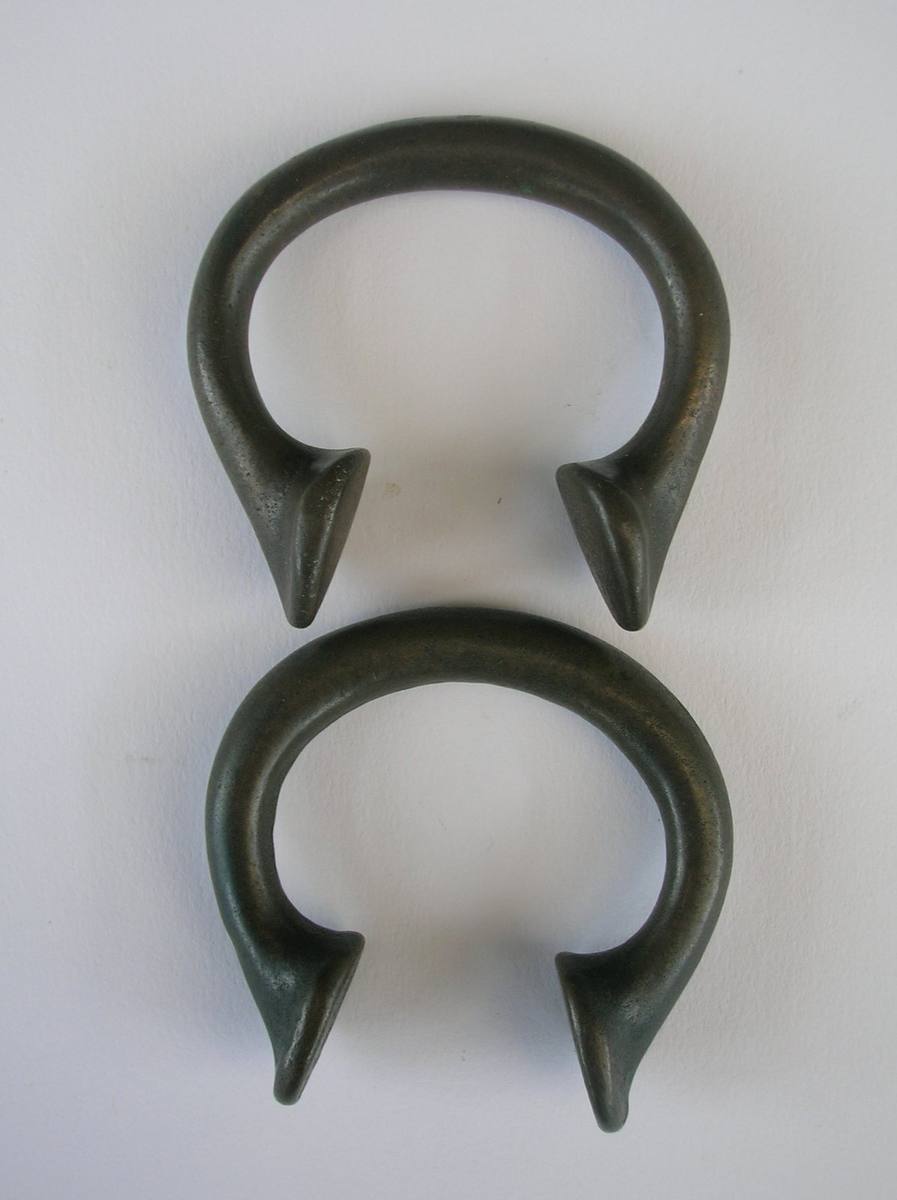 Two bronze manilla rings, Okhapo type, on a neutral background